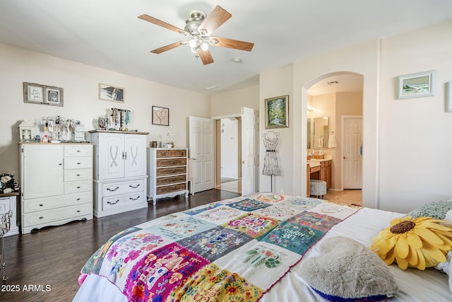 bedroom with arched walkways, ceiling fan, ensuite bath, and wood finished floors