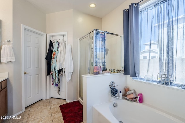 full bathroom featuring a stall shower, tile patterned floors, vanity, and a bath