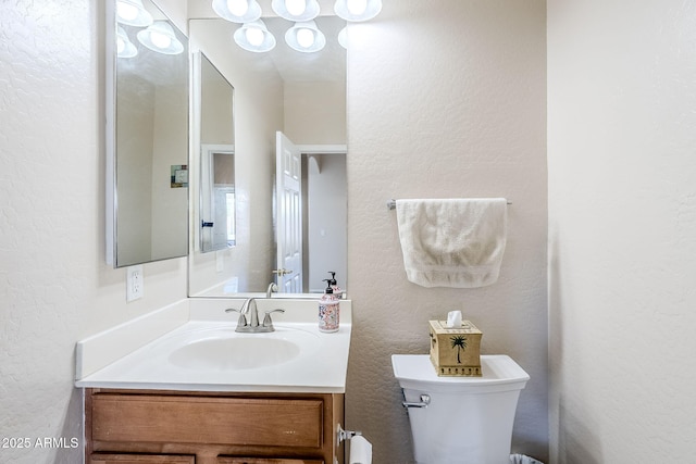 half bathroom with toilet, a textured wall, and vanity