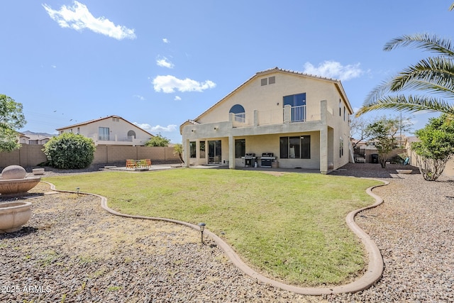 rear view of property featuring a balcony, stucco siding, a fenced backyard, and a patio