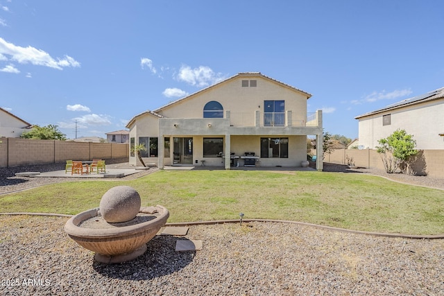 rear view of house featuring a patio, a fenced backyard, a balcony, and stucco siding