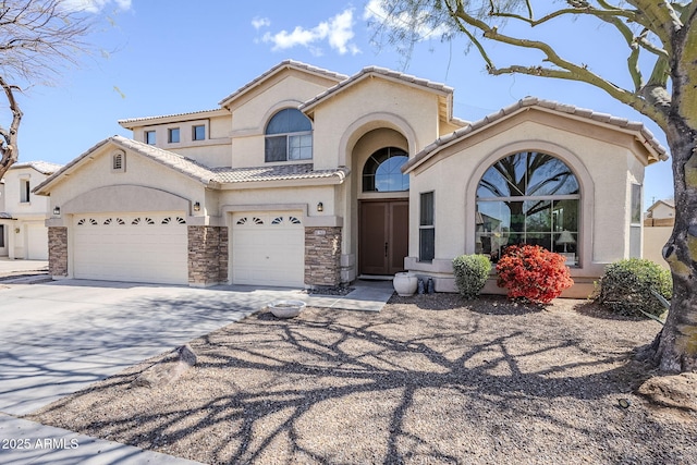 mediterranean / spanish house with concrete driveway, stone siding, a tile roof, and stucco siding