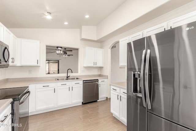 kitchen featuring vaulted ceiling, stainless steel appliances, white cabinets, and sink