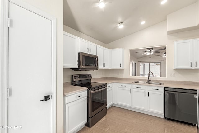 kitchen featuring sink, white cabinets, appliances with stainless steel finishes, and vaulted ceiling