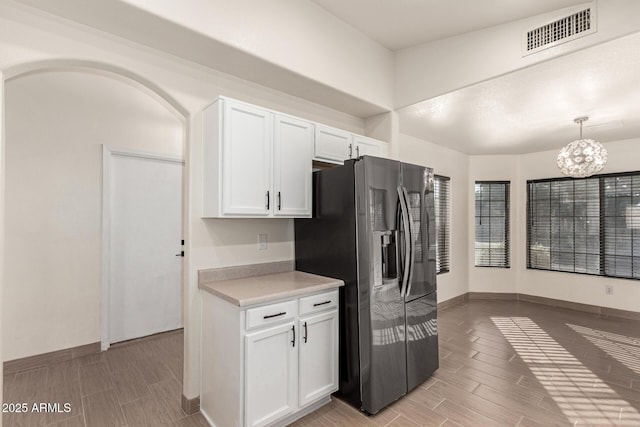 kitchen with decorative light fixtures, stainless steel fridge, an inviting chandelier, and white cabinetry