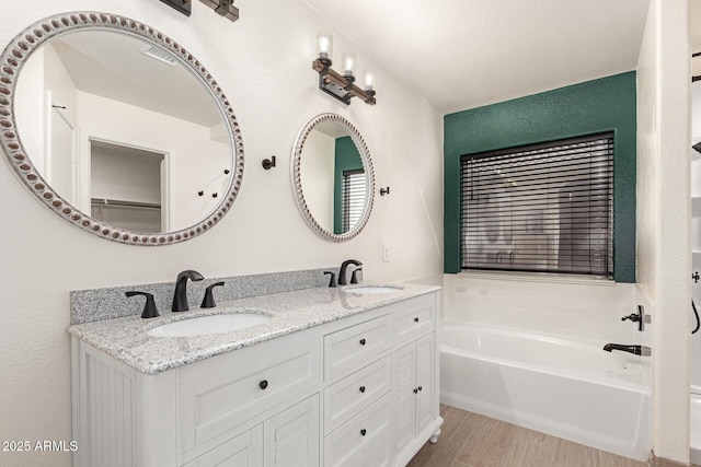 bathroom featuring hardwood / wood-style flooring, a washtub, and vanity