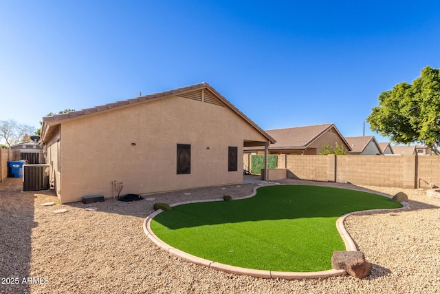 back of house with central air condition unit and a lawn