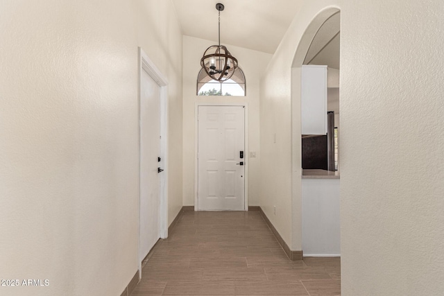 doorway to outside featuring vaulted ceiling and a chandelier