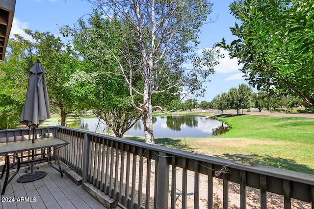 wooden terrace with a water view and a lawn