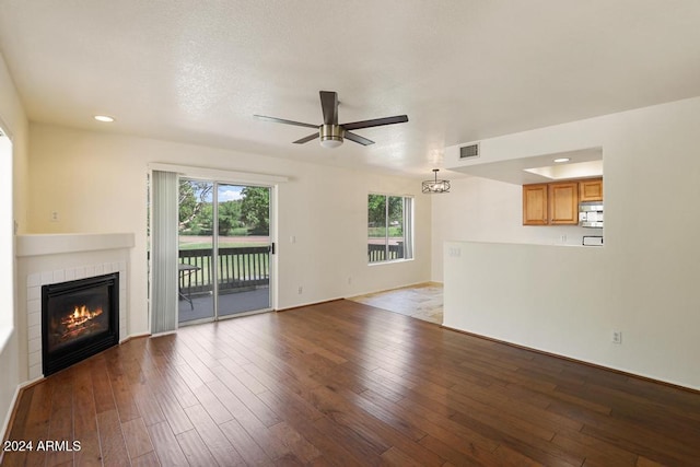 unfurnished living room with a tiled fireplace, ceiling fan, and light hardwood / wood-style flooring