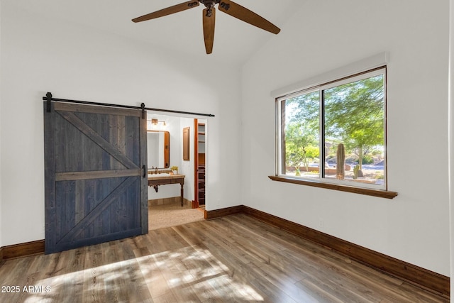 14760 E Paradise Dr, Fountain Hills, AZ 85268 - unfurnished bedroom featuring lofted ceiling, wood finished floors, baseboards, a barn door, and connected bathroom