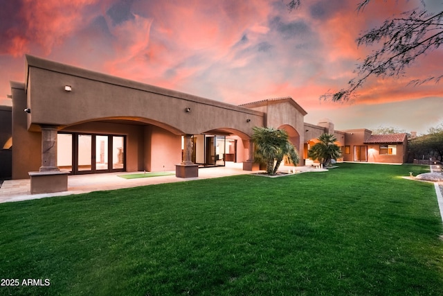 14760 E Paradise Dr, Fountain Hills, AZ 85268 - back of property at dusk featuring a lawn, stucco siding, and a patio area