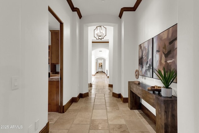 14760 E Paradise Dr, Fountain Hills, AZ 85268 - hallway featuring arched walkways, stone tile flooring, baseboards, ornamental molding, and a chandelier