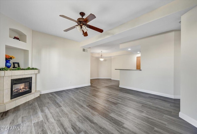 unfurnished living room featuring ceiling fan, a fireplace, and dark wood-type flooring