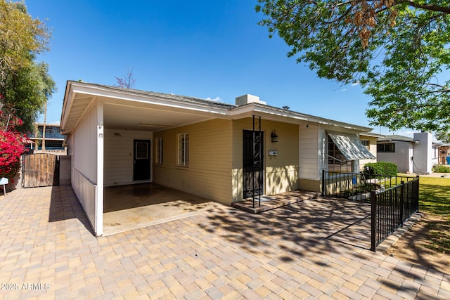 view of front of house featuring a carport, a gate, fence, and decorative driveway