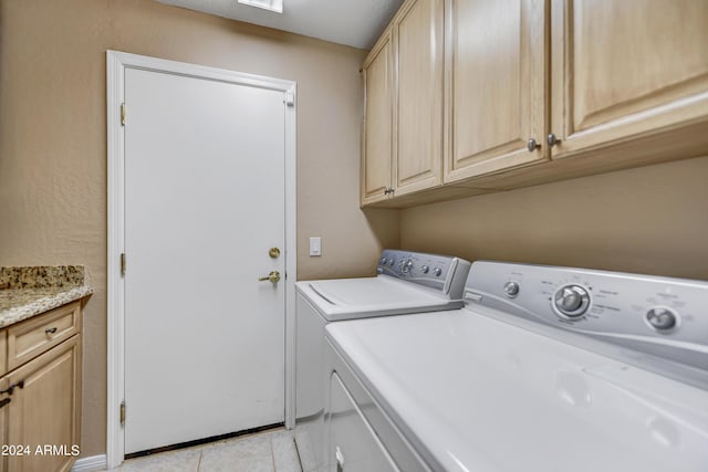 laundry area featuring washer and clothes dryer, cabinets, and light tile patterned flooring