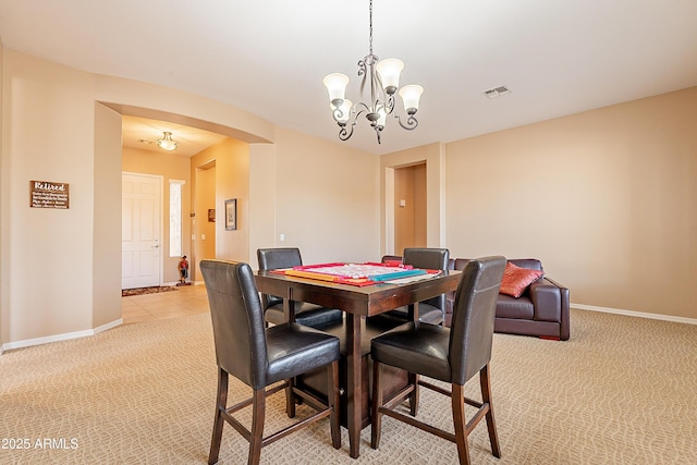 dining space featuring baseboards, a chandelier, visible vents, and light colored carpet