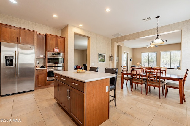 kitchen featuring wallpapered walls, visible vents, appliances with stainless steel finishes, and a kitchen breakfast bar