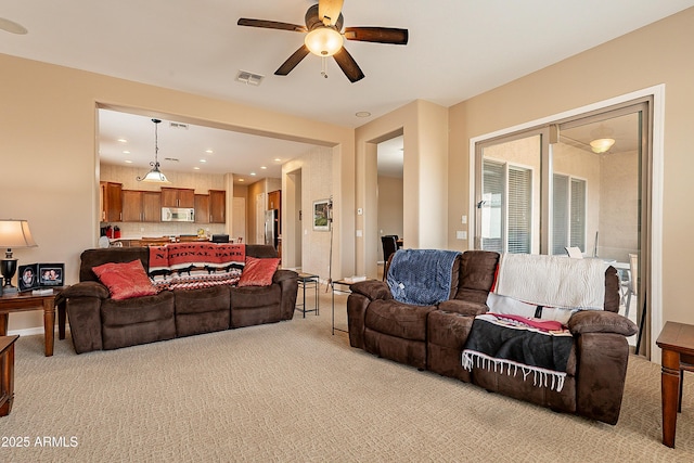 living area with light carpet, visible vents, and a ceiling fan