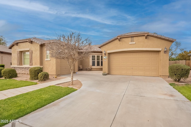 view of front of house featuring a garage, fence, concrete driveway, a tiled roof, and stucco siding