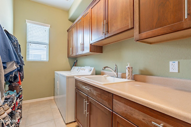 clothes washing area with washing machine and clothes dryer, light tile patterned floors, cabinet space, a sink, and baseboards