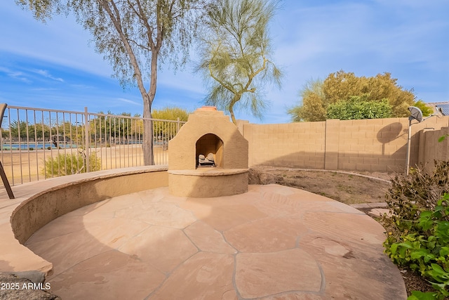 view of patio with fence and exterior fireplace