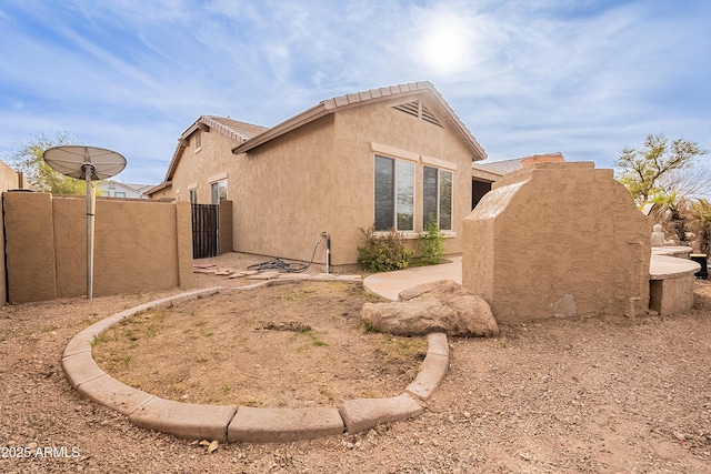 view of side of home with a gate, fence, and stucco siding