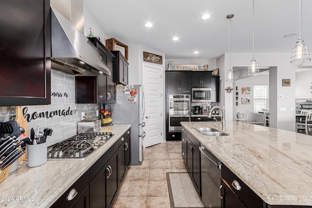 kitchen with backsplash, stainless steel appliances, wall chimney exhaust hood, sink, and pendant lighting