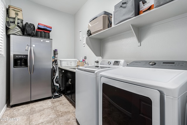 laundry area featuring light tile patterned floors, washing machine and clothes dryer, and cabinets