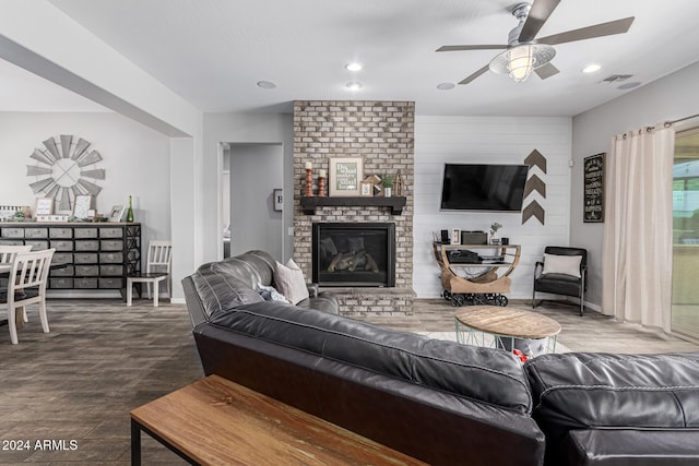 living room featuring brick wall, ceiling fan, dark hardwood / wood-style floors, and a brick fireplace