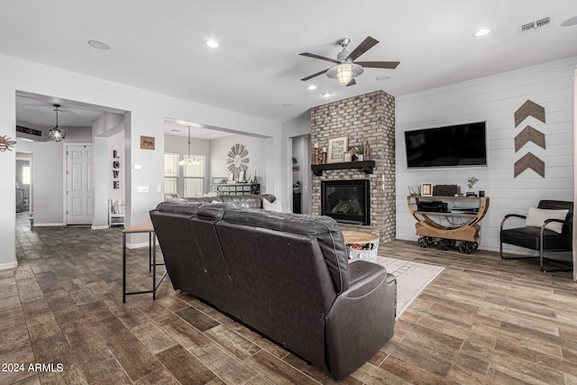 living room with ceiling fan with notable chandelier, dark hardwood / wood-style floors, and a fireplace