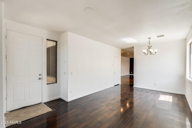 unfurnished room featuring visible vents, baseboards, an inviting chandelier, and wood finished floors
