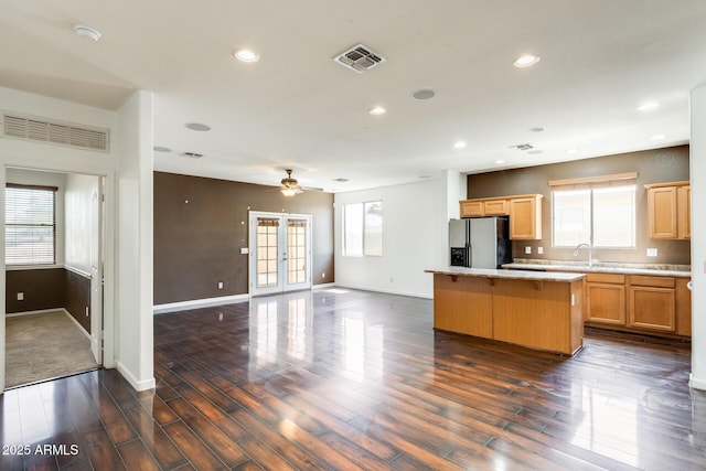 kitchen with a sink, visible vents, refrigerator with ice dispenser, and a kitchen island