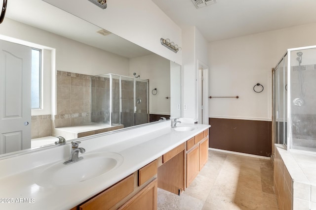 bathroom featuring a shower stall, double vanity, and a sink