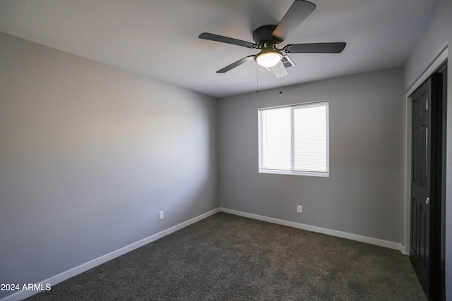 unfurnished room with ceiling fan and dark colored carpet