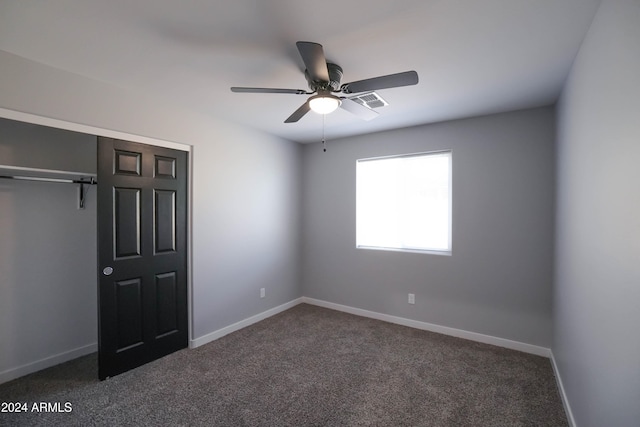 unfurnished bedroom featuring ceiling fan, dark carpet, and a closet