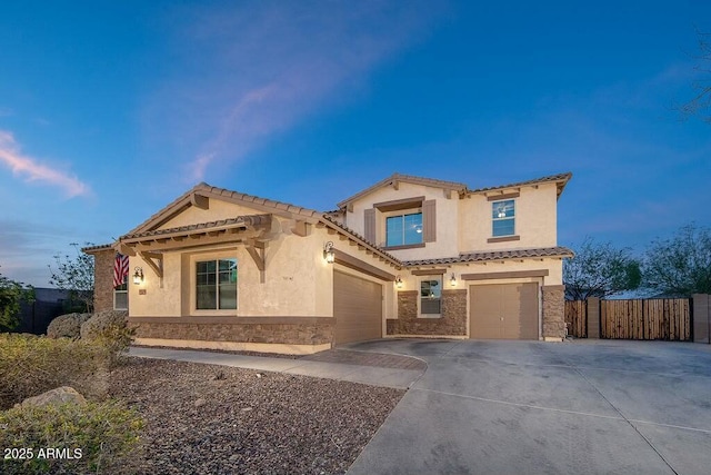 mediterranean / spanish home with fence, stucco siding, a garage, stone siding, and driveway