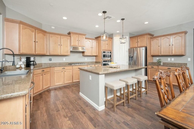 kitchen with light brown cabinetry, visible vents, under cabinet range hood, and a sink