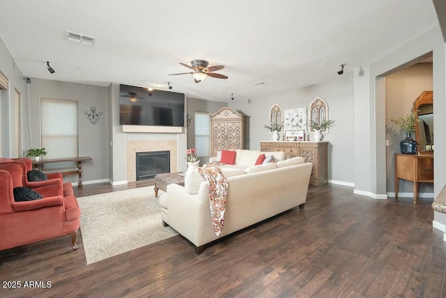 living room featuring visible vents, a tile fireplace, baseboards, and dark wood-style flooring