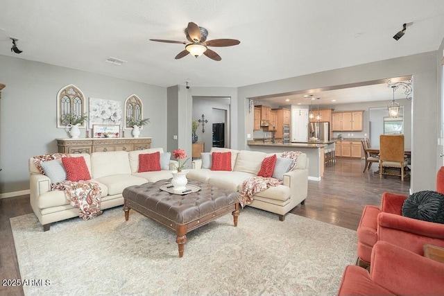 living area with baseboards, visible vents, dark wood-style flooring, and ceiling fan