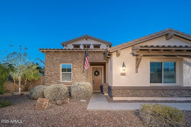 mediterranean / spanish-style house with stucco siding, stone siding, and a tiled roof