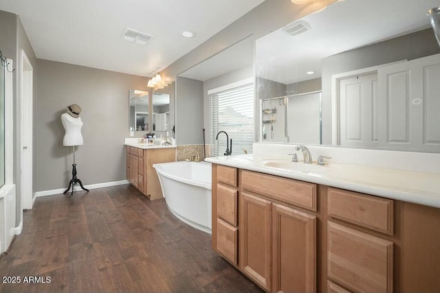 bathroom featuring a sink, visible vents, wood finished floors, and a stall shower