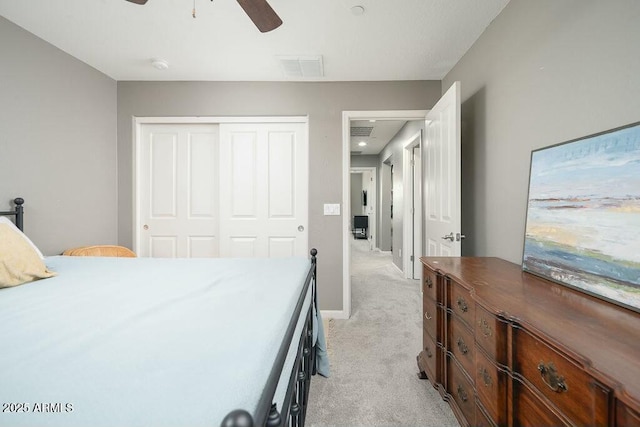 bedroom with visible vents, baseboards, ceiling fan, light colored carpet, and a closet