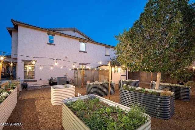 rear view of house with a garden, stucco siding, and a fenced backyard