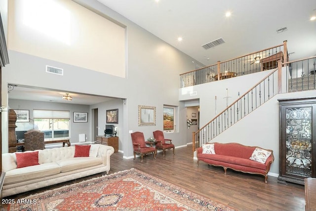 living area with visible vents, baseboards, wood finished floors, and stairway