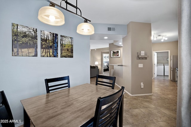 3236 E Chandler Blvd Unit 2018, Phoenix, AZ 85048 - dining room featuring washing machine and dryer, track lighting, decorative columns, and tile patterned flooring