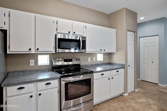 3236 E Chandler Blvd Unit 2018, Phoenix, AZ 85048 - kitchen featuring appliances with stainless steel finishes, dark countertops, white cabinetry, light tile patterned floors, and recessed lighting