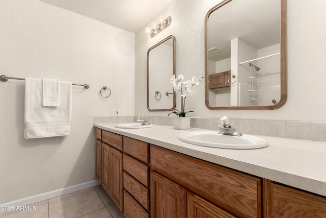 bathroom featuring double vanity, baseboards, a sink, and tile patterned floors