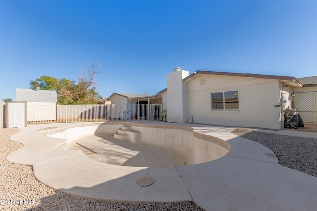 rear view of property featuring a patio area, a fenced backyard, and a chimney