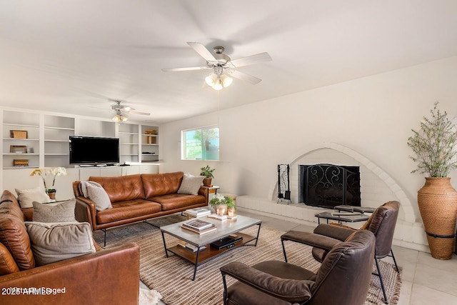 living room featuring a tile fireplace, light tile patterned flooring, and ceiling fan